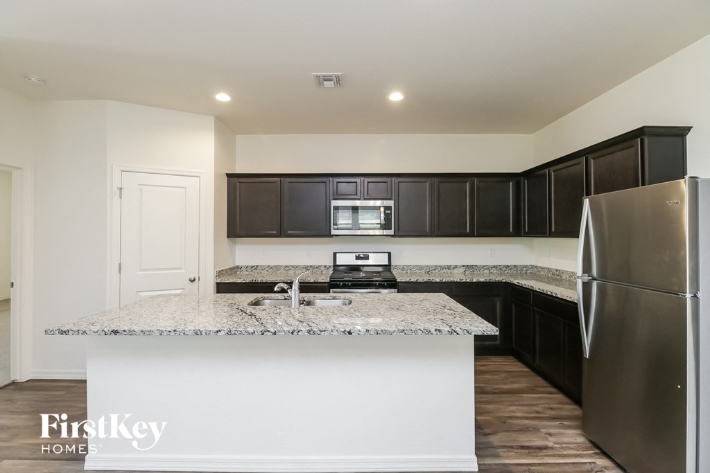 A kitchen with a granite countertop and stainless steel appliances.