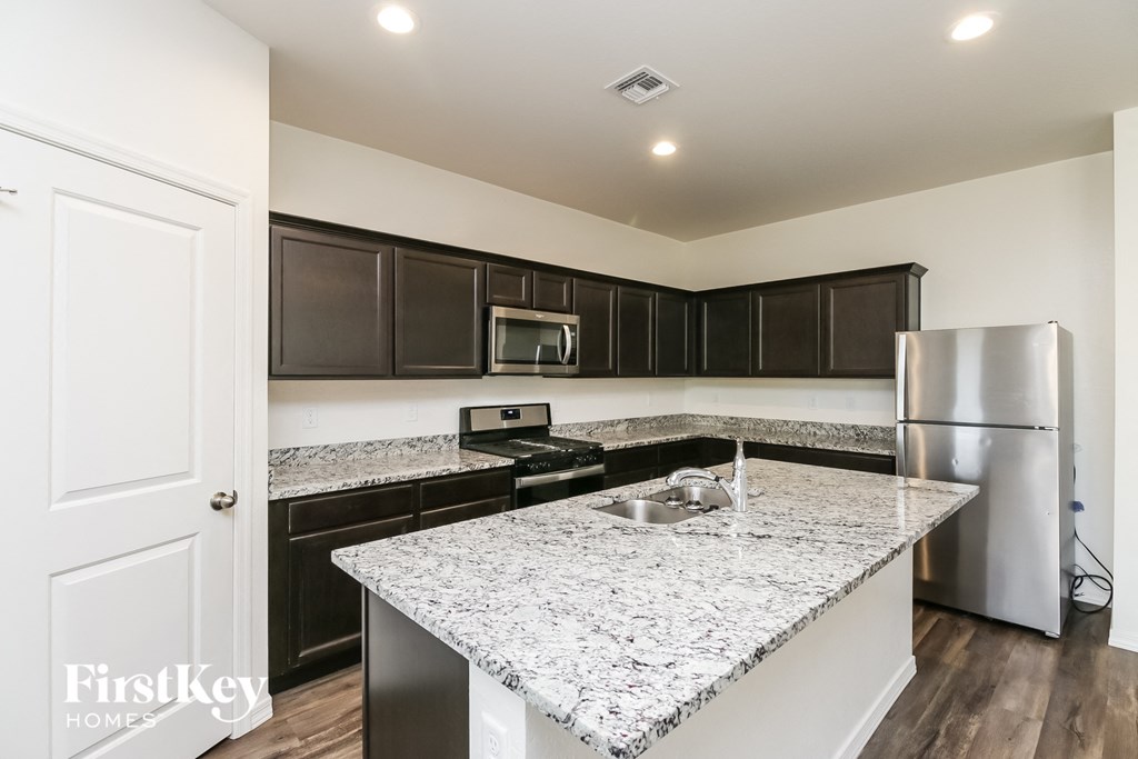 A kitchen with a granite countertop and stainless steel appliances.