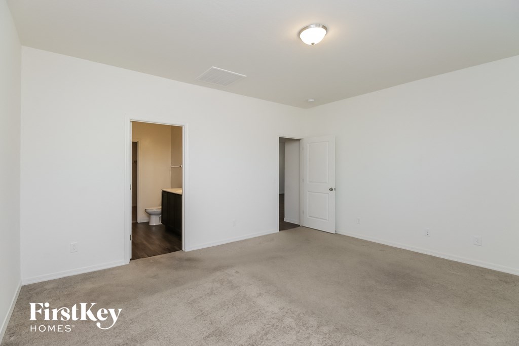 A spacious room with a carpeted floor and two doors, one of which is open to a bathroom.