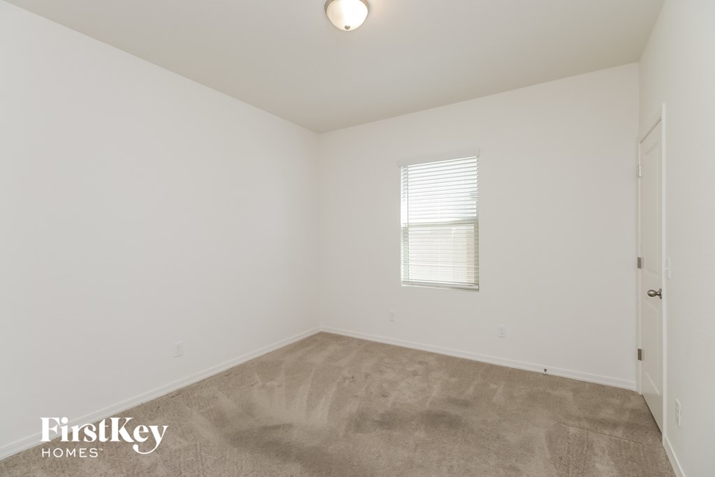A room with a carpeted floor and a window with blinds.