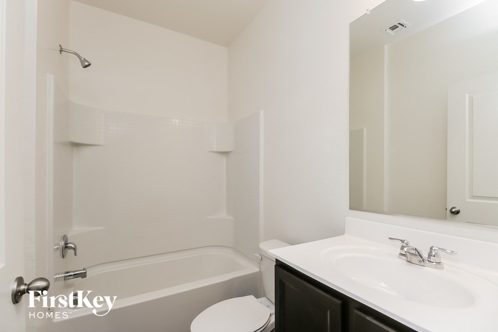A white bathroom with a tub, toilet and sink.