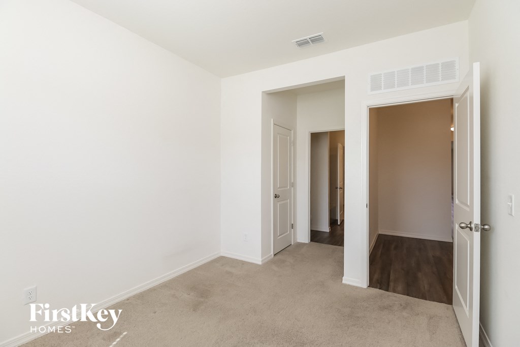A white room with a carpeted floor and a doorway leading to another room.