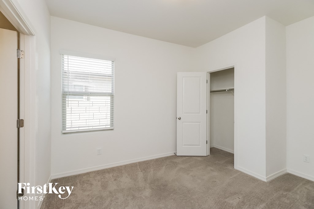 A room with a carpeted floor and a window with blinds.