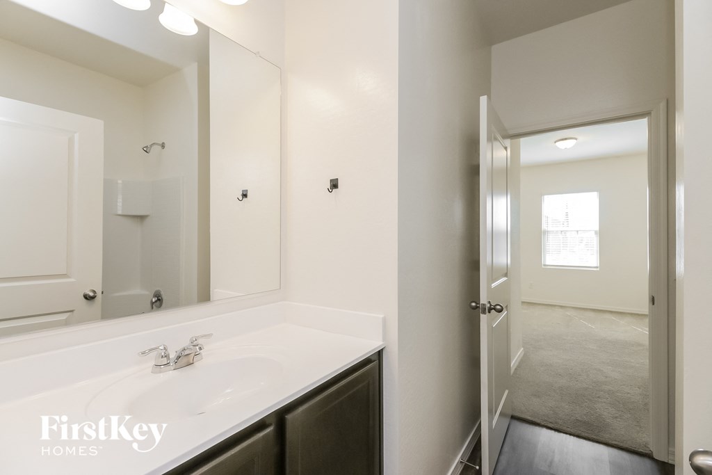 A bathroom with a white counter top and a mirror above it.