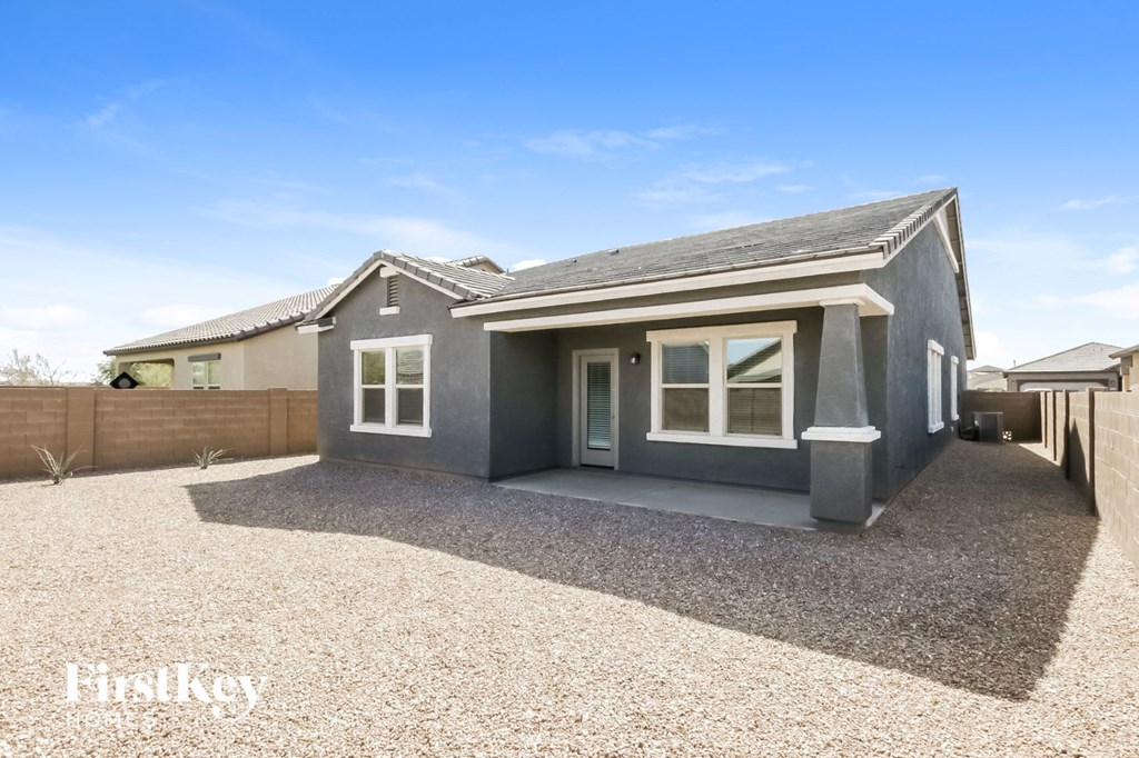 A grey house with a gravel driveway in front.