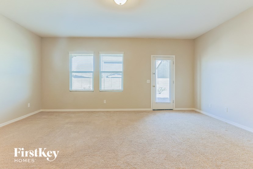 an empty living room with two windows and a door