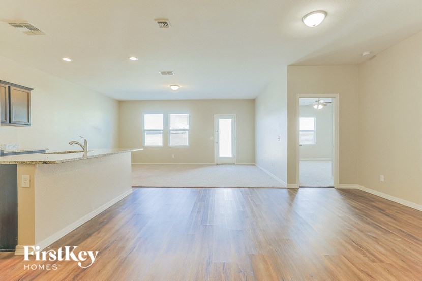 an empty living room and kitchen with wood flooring