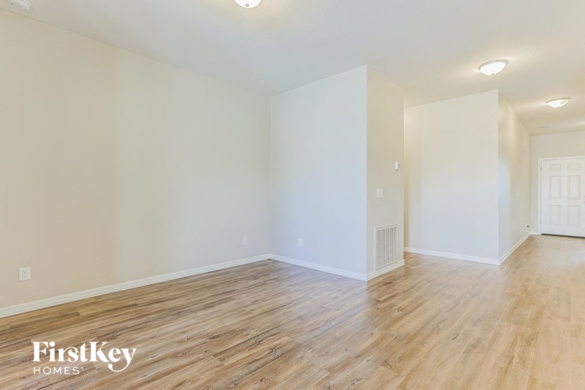the living room and dining room with wood floors and white walls
