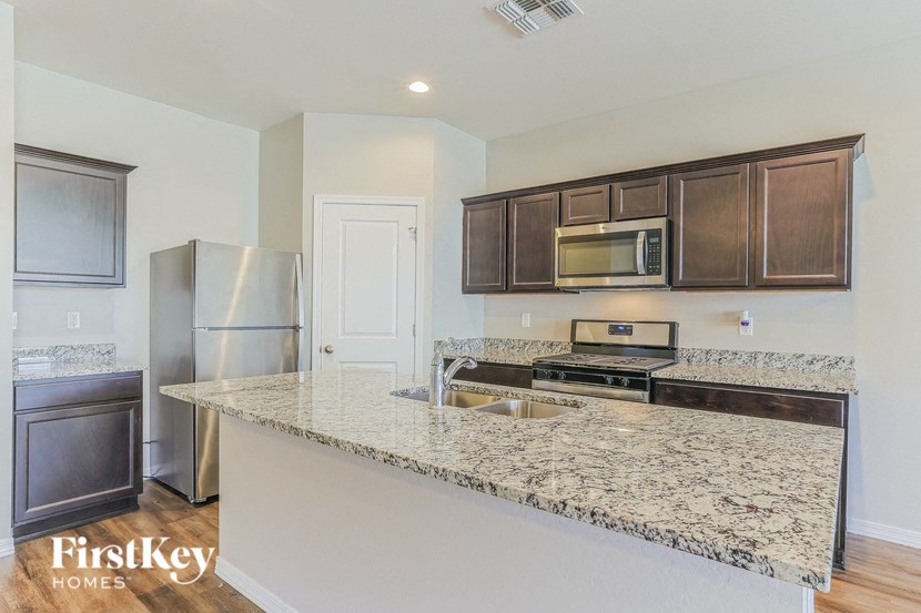 a kitchen with a granite counter top and a stainless steel refrigerator