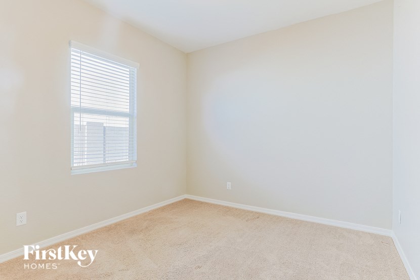 a bedroom with white walls and white carpet and a window
