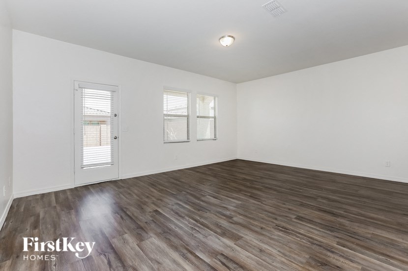 A room with wooden flooring and two windows.