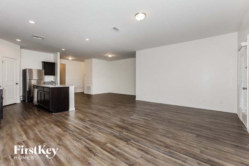 A spacious room with wooden flooring and white walls.