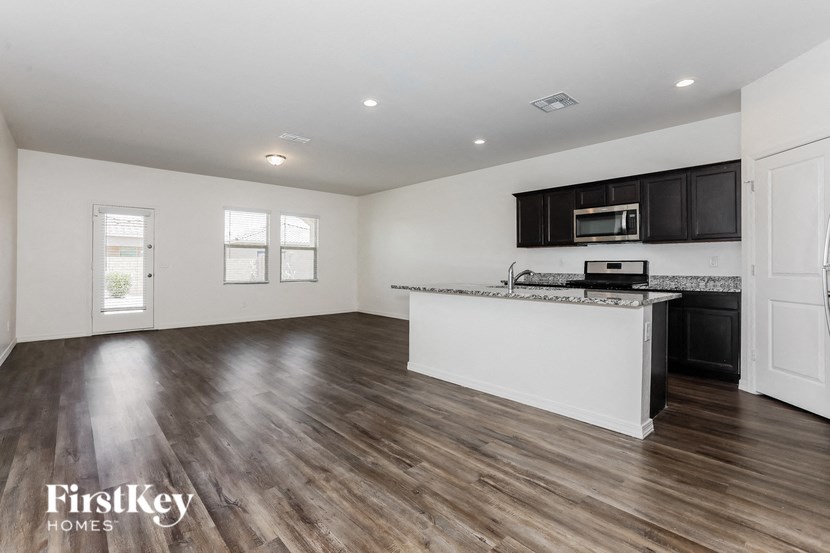 A spacious kitchen and living room with wooden floors and white walls.