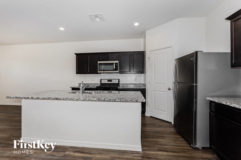 A kitchen with a white island and black appliances.