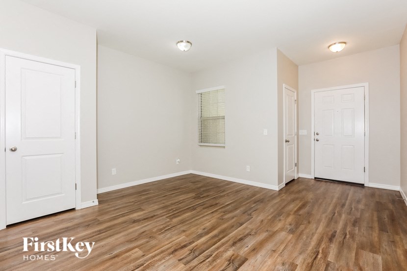 an empty living room with wood flooring and white doors