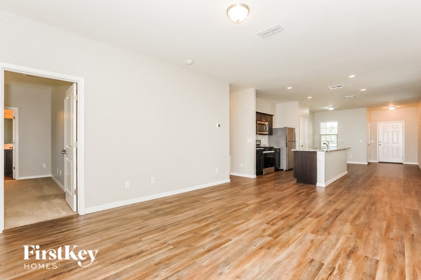 an empty living room and kitchen with wood flooring