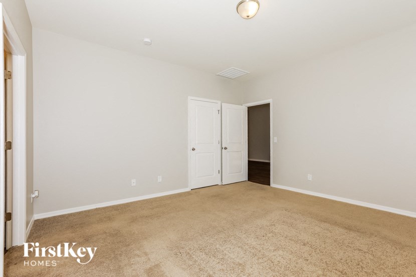 a bedroom with a carpeted floor and a door to a closet