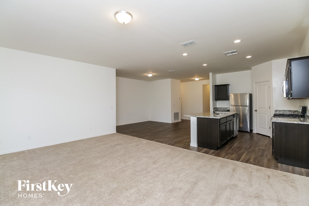 an empty living room with a kitchen and a tv