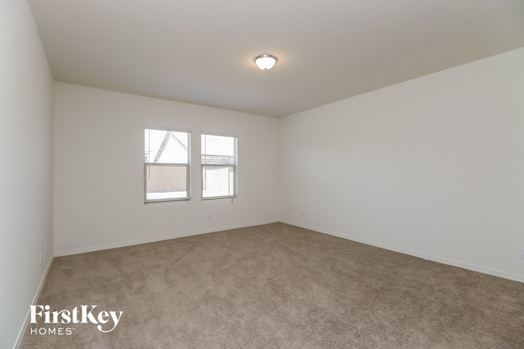 a bedroom with white walls and carpet and a window