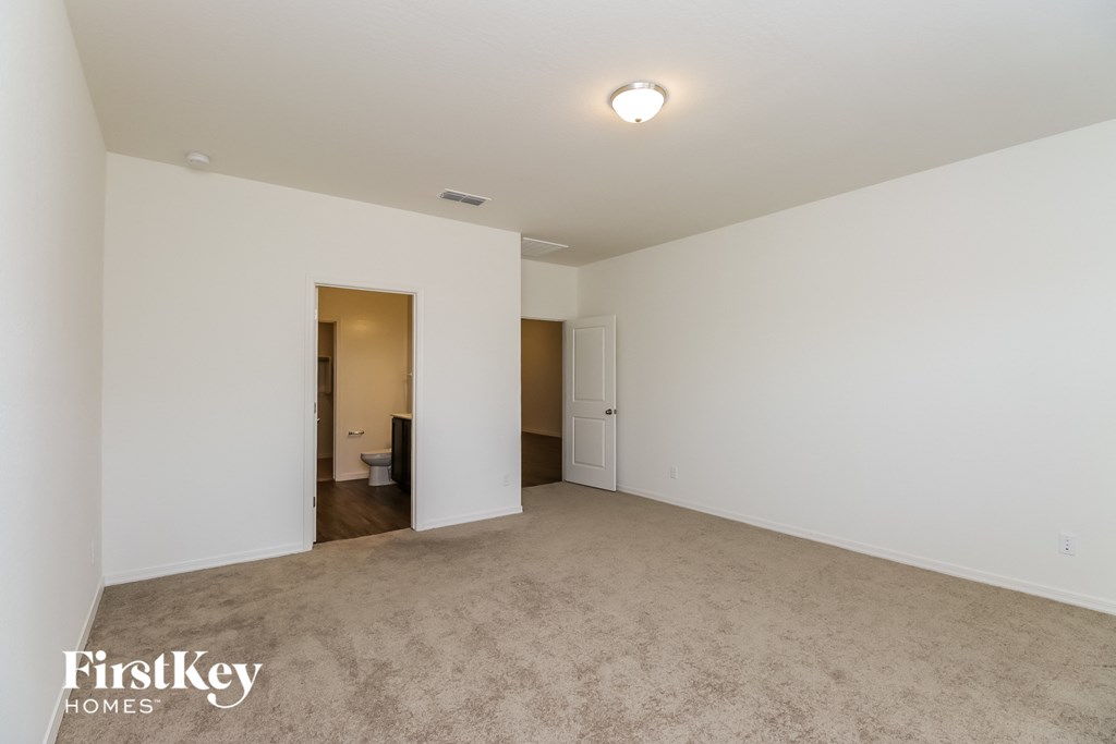 a spacious living room with white walls and carpet