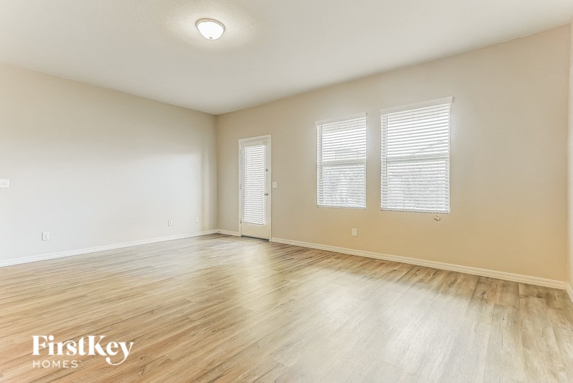 the spacious living room with wood flooring and white walls