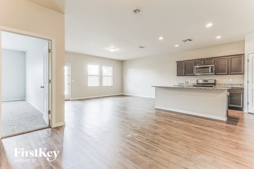 an empty living room and kitchen with wood flooring