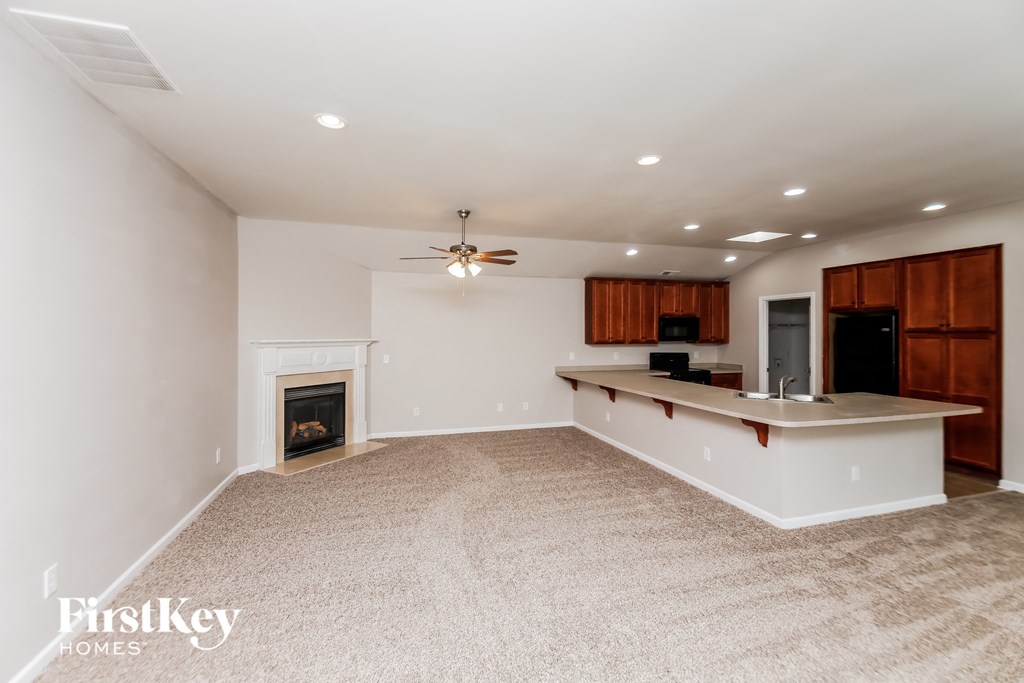 an empty living room with a fireplace and a kitchen