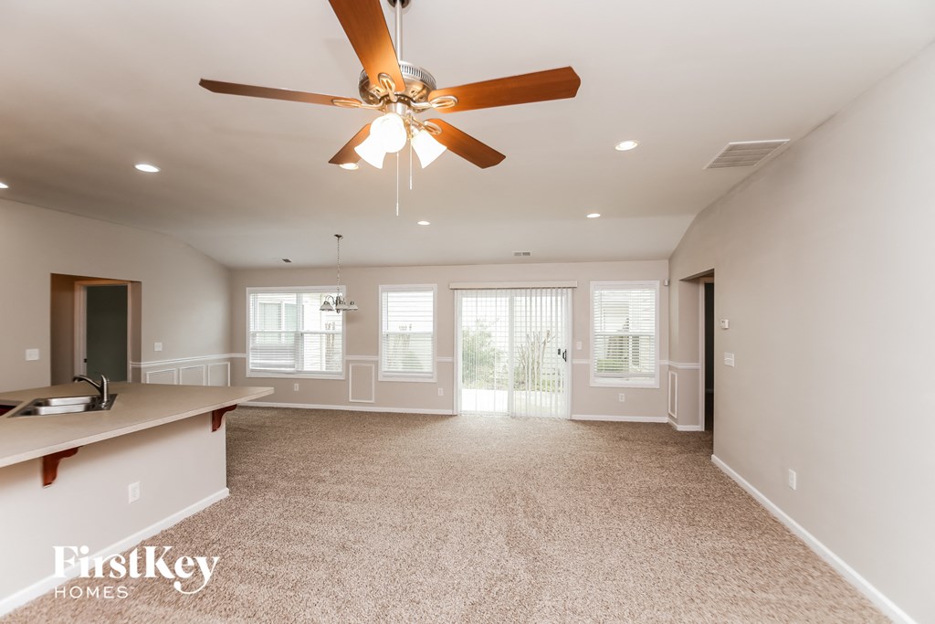 an empty living room with a ceiling fan and a window