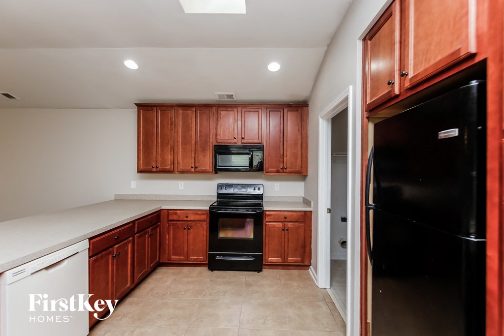 a kitchen with wooden cabinets and black appliances and a black refrigerator