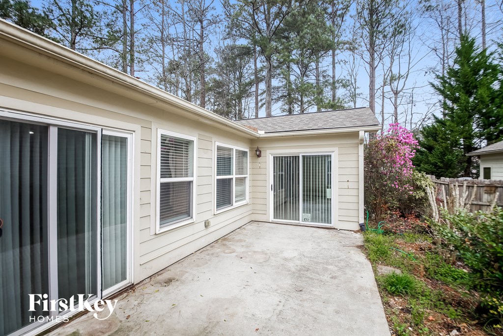 a side view of a white house with a concrete driveway and a door way