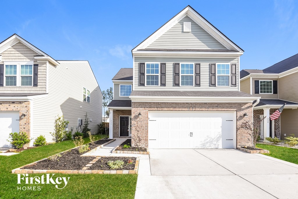 A house with a garage and a driveway in front of it.