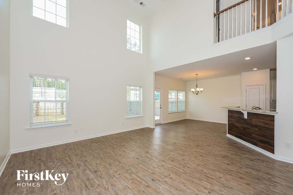 A spacious room with wooden floors and a balcony on the upper floor.