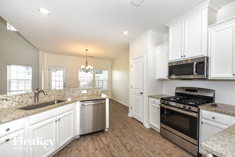 A kitchen with white cabinets and a granite countertop.