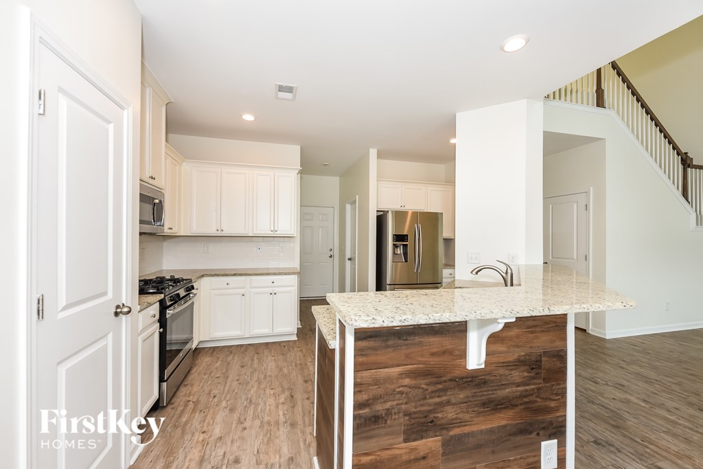 A kitchen with white cabinets and a wooden island.