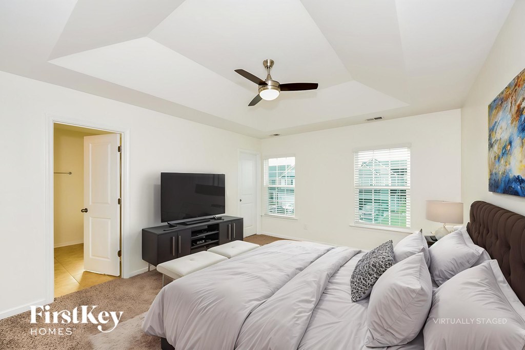 A bedroom with a bed, a television, and a painting on the wall.