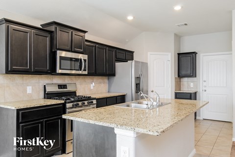 A kitchen with black cabinets and a granite countertop.