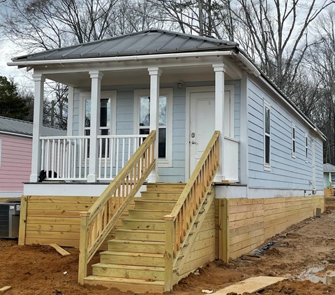 a small blue house with a porch and a staircase