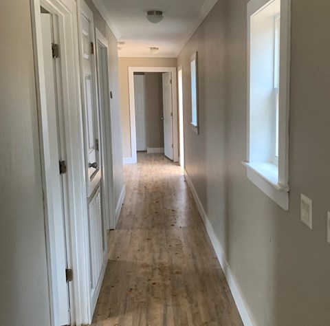 a long hallway with wood floors and white walls and a door