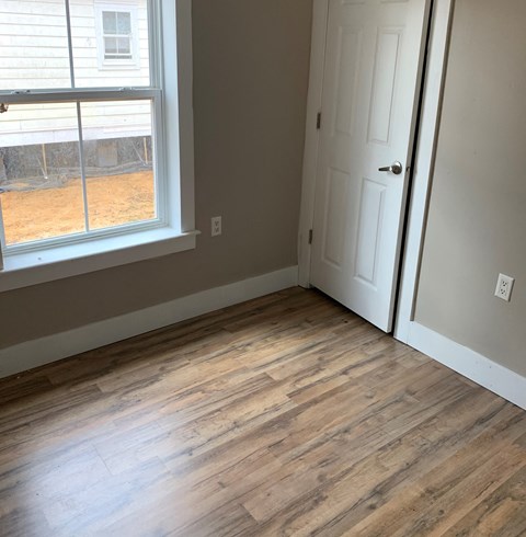 an empty room with wood floors and a window