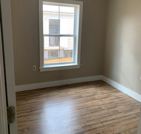 an empty room with wooden floors and a window