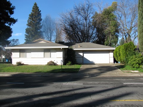 A white house with a grey roof and a garage door.