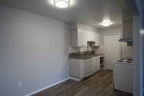 A kitchen with white cabinets and a wooden floor.