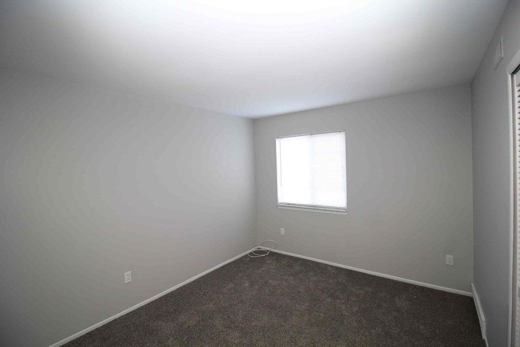 A room with a window and carpeted floor.