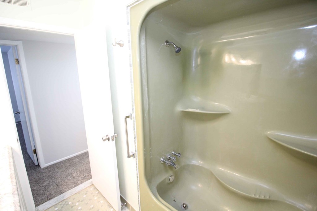 A white bathroom with a white tub and a white door.