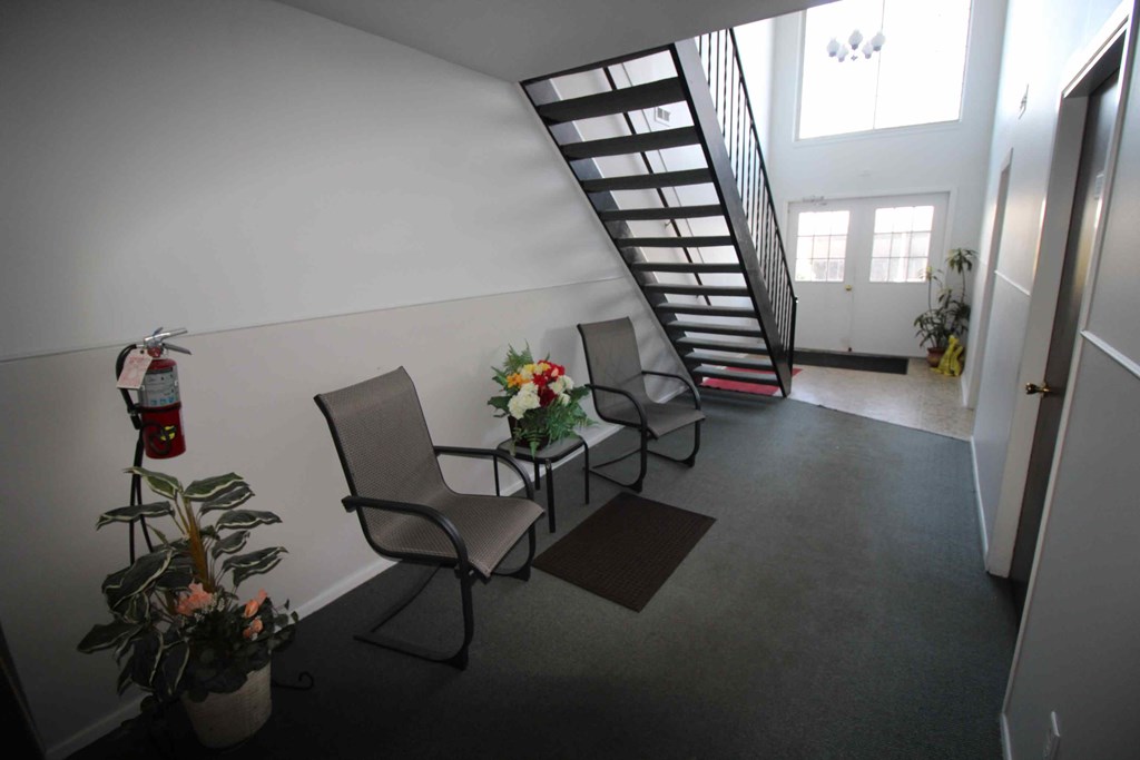 A living room with a chair, a plant, and a staircase.