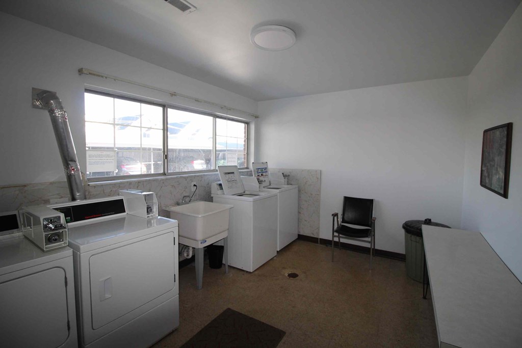 A room with a washing machine, dryer, and sink.