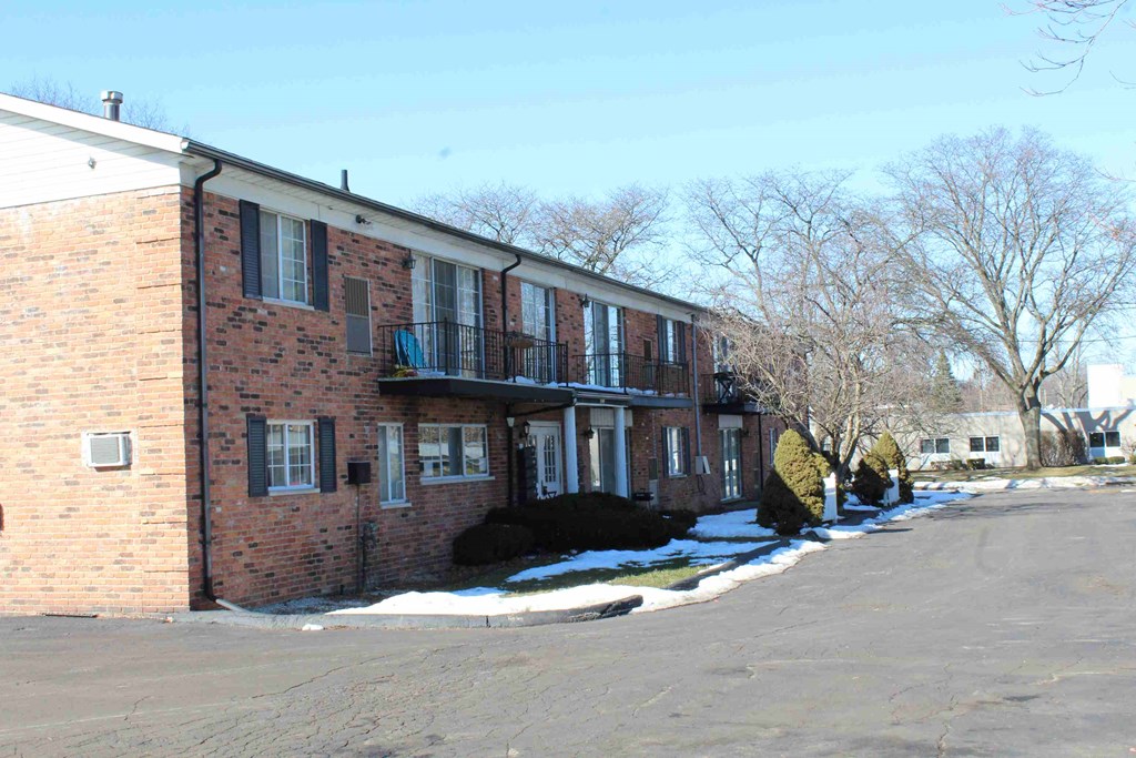 A brick building with a black awning and a tree with no leaves.