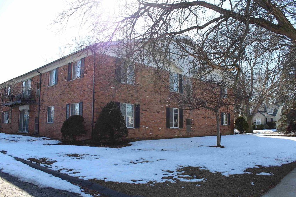 A red brick building with a tree in front of it.