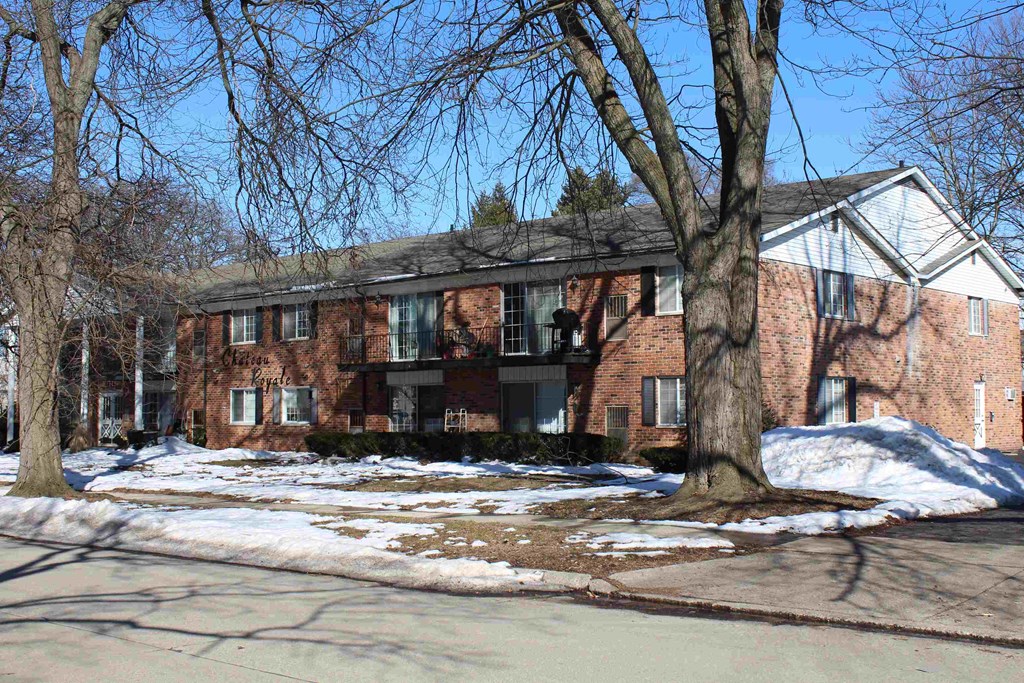 A red brick building with a white roof and a tree in front.