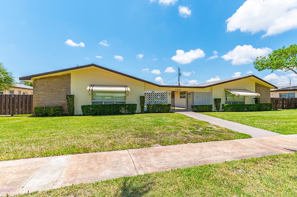 a yellow house with a yard and a sidewalk